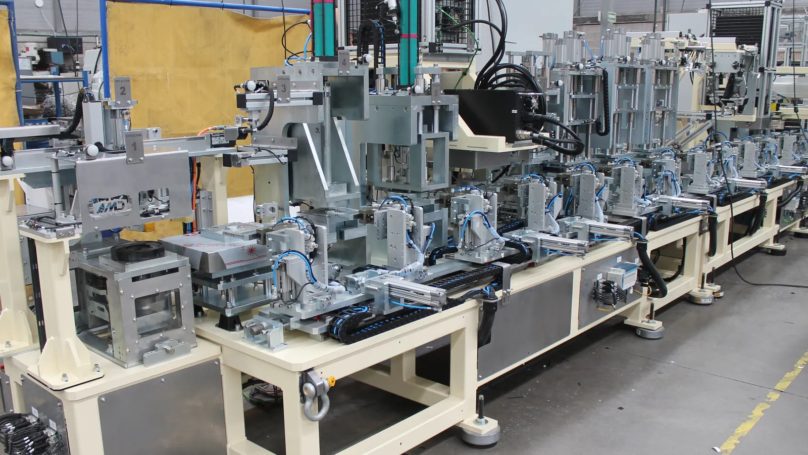 Linear transfer assembly machine with numbered press, gripper and laser-marking stations, built by AMD Machines