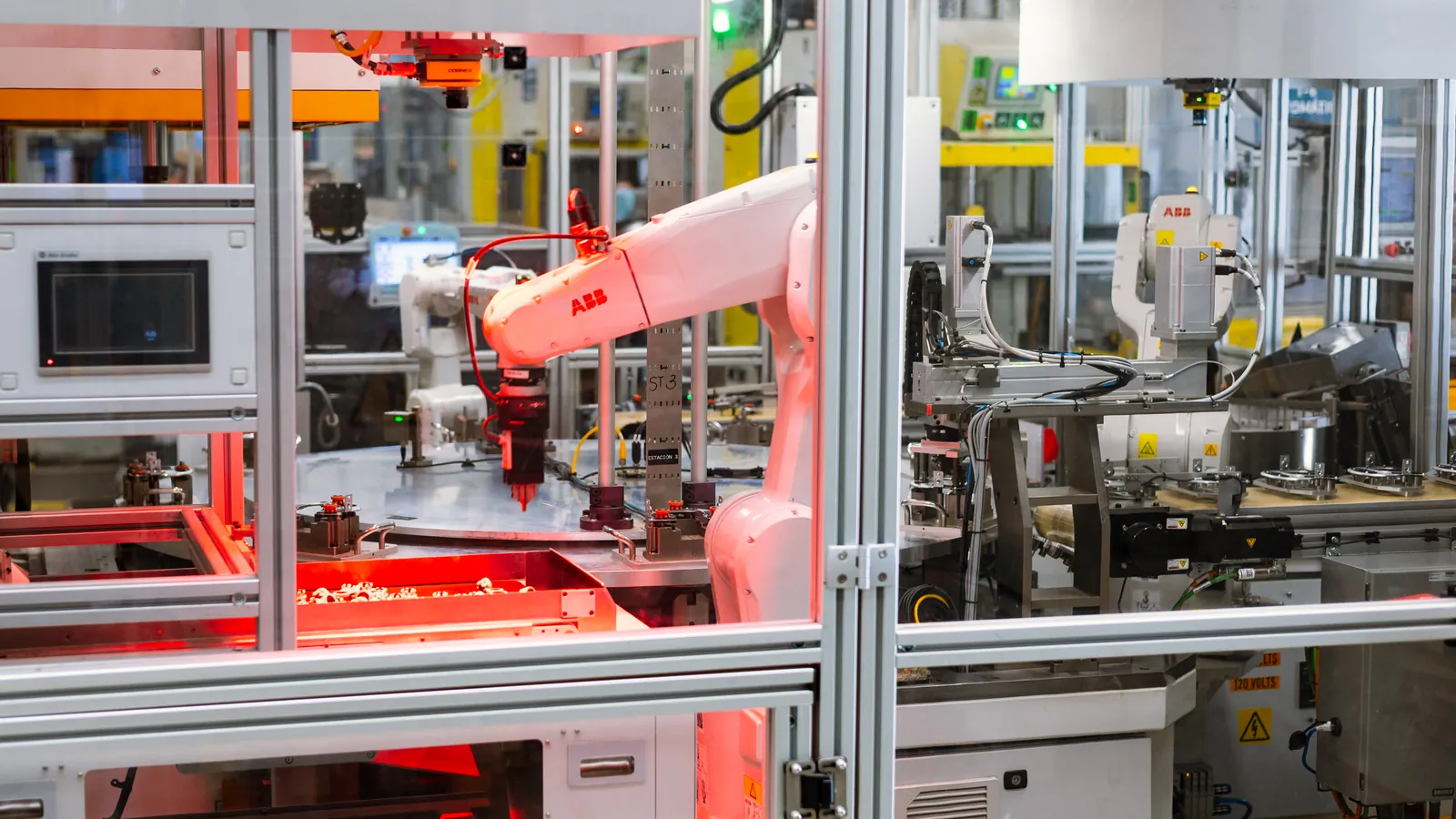 Rotary-dial assembly cell with ABB robots, a Cognex camera over a lit parts tray and a bulk hopper, built by AMD Machines