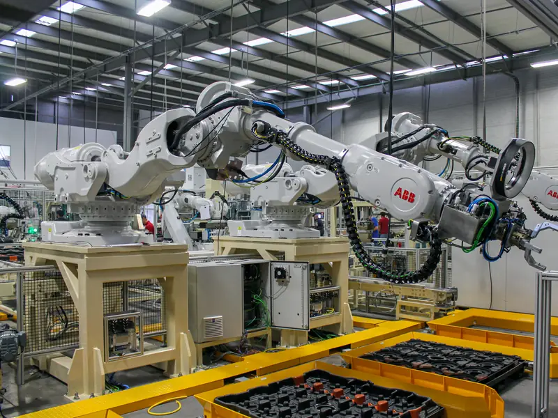 ABB robots handling parts between trays in a production cell built by AMD Machines