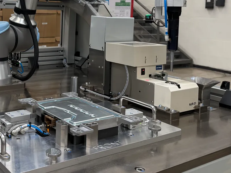 Cobot screwdriving station: screwdriver spindle at an Ohtake screw presenter beside a part nest, built by AMD Machines