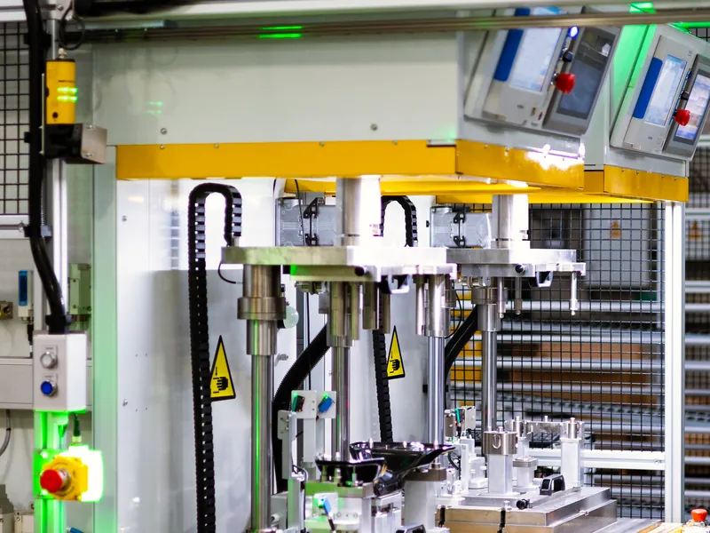 Two-station press assembly machine with guided press rams above part nests, built by AMD Machines