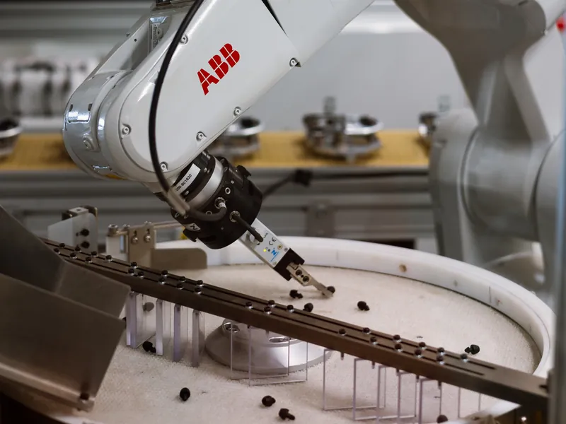 ABB robot gripper picking small black parts off a round flexible feeder disc, built by AMD Machines