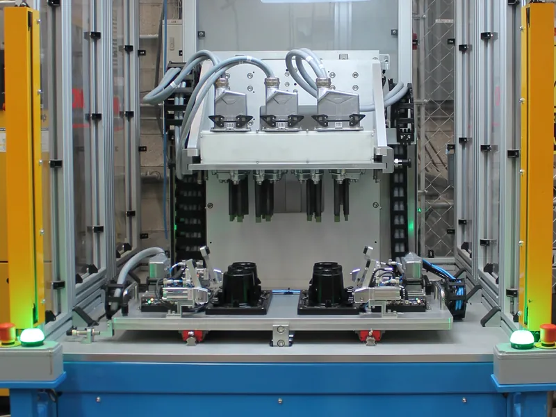 Heat staking station: staking head over plastic parts in two shuttle nests, between light curtains, built by AMD Machines