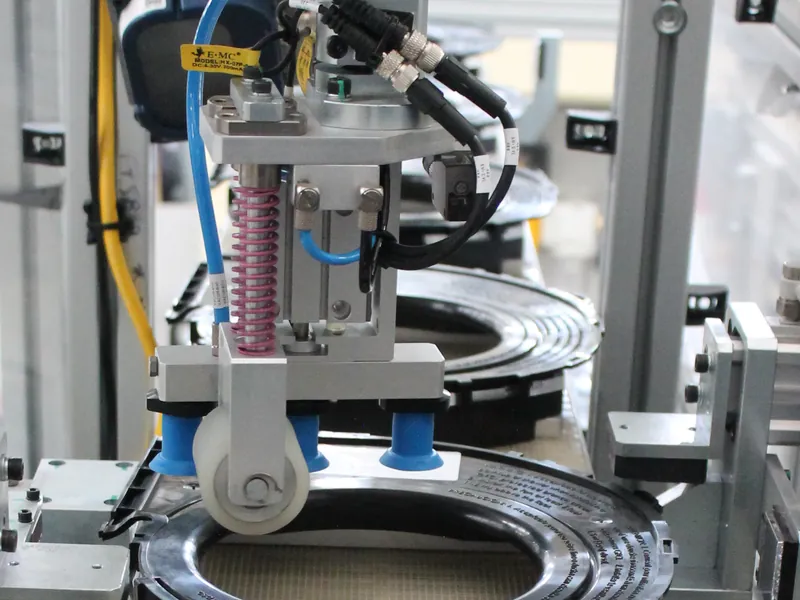 Label applicator head with vacuum cups and a roller placing a label on a molded part, built by AMD Machines