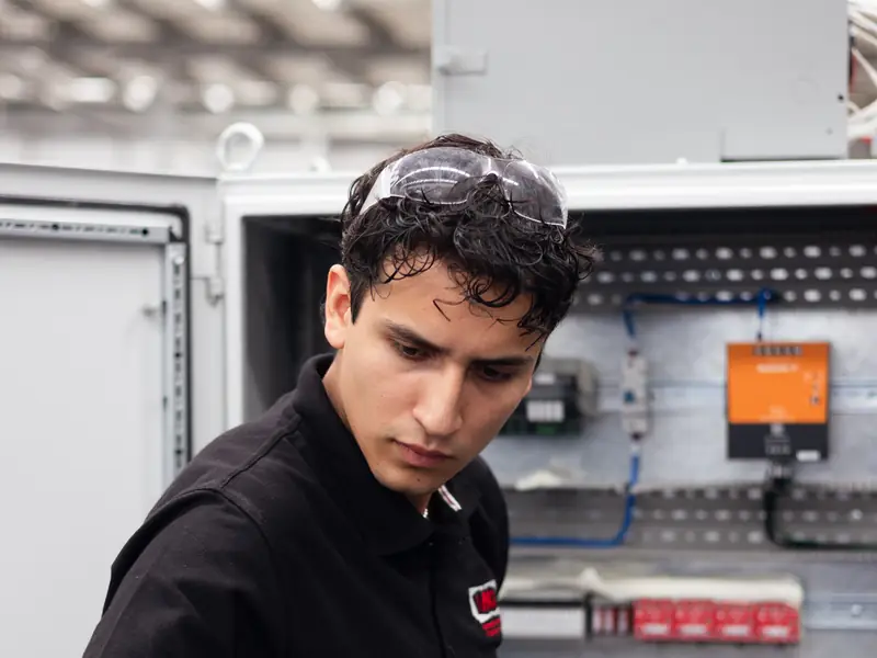 AMD Machines technician troubleshooting an electrical control panel